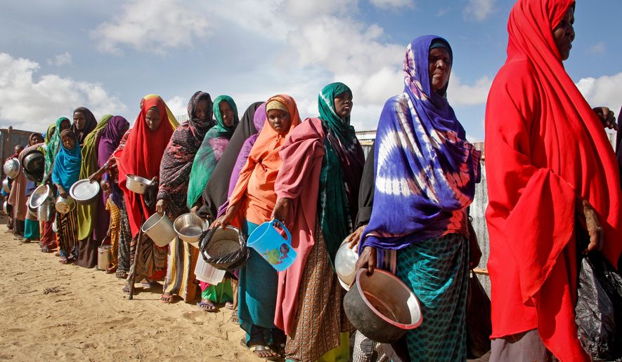 In this May 18, 2019 file photo, newly-arrived women who fled drought line up to receive food distributed by local volunteers at a camp for displaced persons in the Daynile neighborhood on the outskirts of the Somalian capital Mogadishu. (AP Photo/Farah Abdi Warsameh, file)
