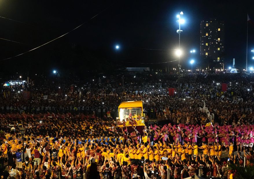 Catholic devotees walk beside a glass-covered carriage carrying the image of Jesus Nazareno during its annual procession in Manila, Philippines, on its feast day, Friday Jan. 9, 2026. (AP Photo/Aaron Favila)