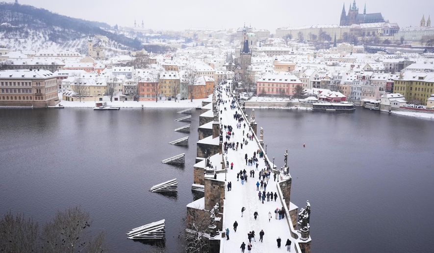 People cross the medieval Charles Bridge after a heavy snowfall in Prague, Czech Republic, Friday, Jan. 9, 2026. (AP Photo/Petr David Josek)