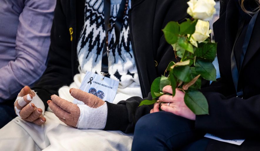 A victim with burned hands and relatives attend the official commemorative ceremony for the victims of the deadly fire at the "Le Constellation" bar in Crans-Montana, in Martigny, Switzerland, Friday, Jan. 9, 2026. (Laurent Gillieron/Keystone/Pool via AP)