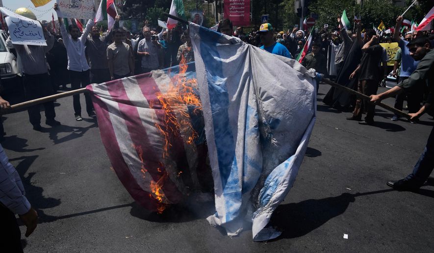 FILE - Iranian protestors burn representations of the Israeli and U.S. flags during a protest to condemn Israeli attacks on multiple cities across Iran, after the Friday prayers ceremony in Tehran, Iran, Friday, June 20, 2025. (AP Photo/Vahid Salemi), File)