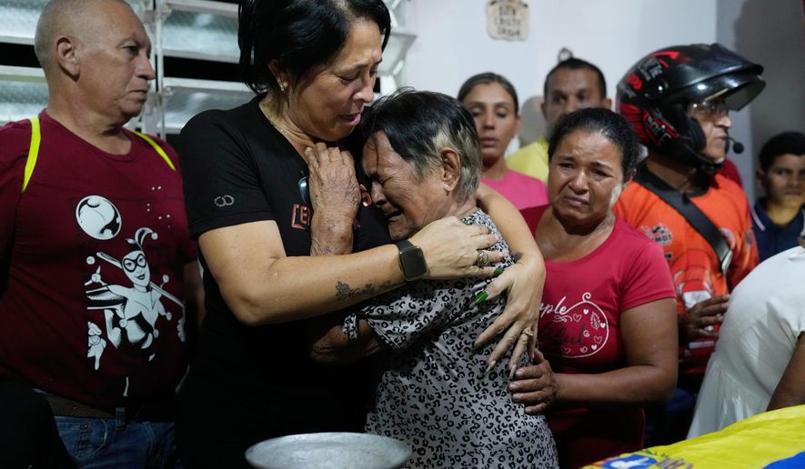 Emelyn Torres and Maria Cristina Fernandez, the sister and grandmother of Edilson Torres, a Venezuelan police officer who died in prison after being detained on accusations of treason, embrace during his wake at his home in Guanare, Venezuela, Monday, Jan. 12, 2026. (AP Photo/Ariana Cubillos)