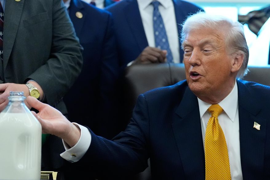 President Donald Trump gestures to a container of milk before he signs a bill that returns whole milk to school cafeterias across the country, in the Oval Office of the White House, Wednesday, Jan. 14, 2026, in Washington. (AP Photo/Alex Brandon)