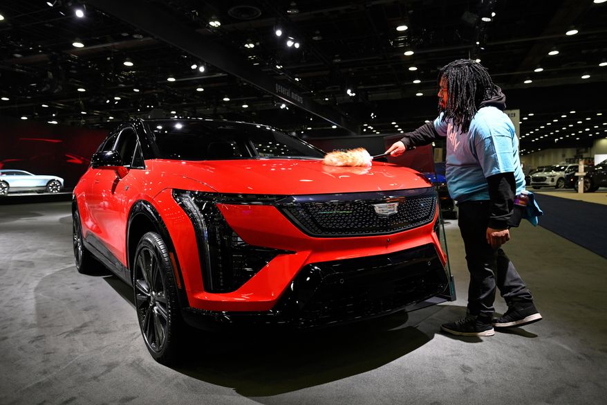 A worker dusts on a 2026 Cadillac Optiq Premium Sport vehicle at the Detroit Auto Show, Wednesday, Jan. 14, 2026, in Detroit. (AP Photo/Jose Juarez)