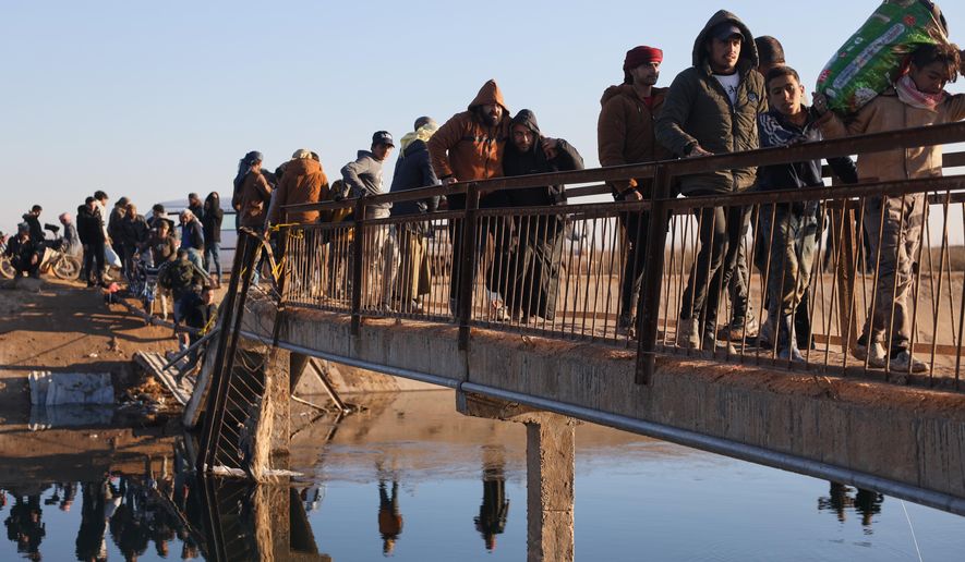 Displaced Syrians at a river crossing near the village of Jarirat al Imam, in the eastern Aleppo countryside, near the front line with the Kurdish-led Syrian Democratic Forces in Deir Hafer, Syria, Thursday, Jan. 15, 2026. (AP Photo/Omar Albam)