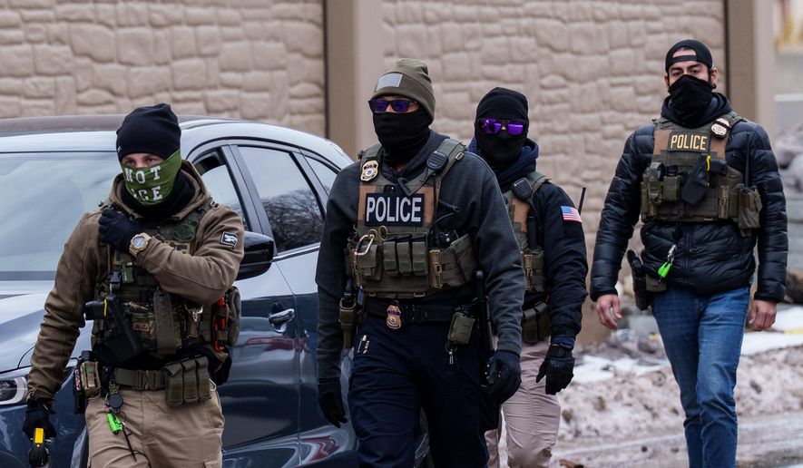 Immigration and Customs Enforcement (ICE) agents, including one wearing a 'NOT ICE' face covering, walk near their vehicles, Thursday, Jan. 15, 2026, in Richfield, Minn. (AP Photo/Adam Gray)