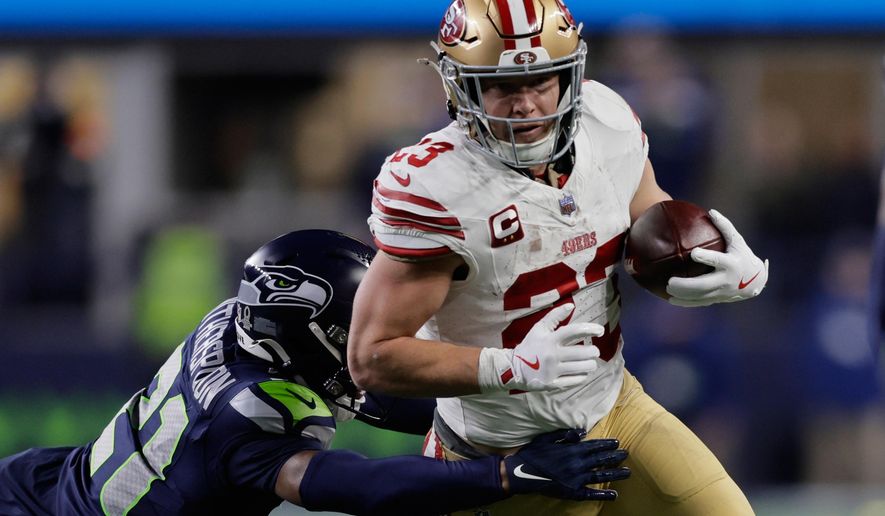 San Francisco 49ers running back Christian McCaffrey (23) tries to get past the Seattle Seahawks cornerback Devon Witherspoon during the first half of an NFL football divisional playoff game Saturday, Jan. 17, 2026, in Seattle. (AP Photo/John Froschauer)
