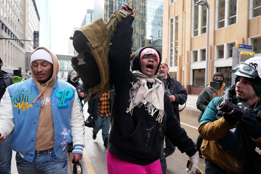 A pro-immigration protester lifts up Jake Lang's vest after an altercation at the March Against Minnesota Fraud rally near Minneapolis City Hall, Saturday, Jan. 17, 2026, in Minneapolis. (AP Photo/Yuki Iwamura)