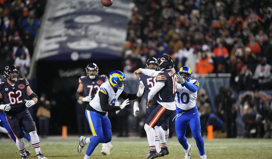 Chicago Bears quarterback Caleb Williams (18) throws a touchdown pass to tight end Cole Kmet, not visible, as Los Angeles Rams linebacker Josaiah Stewart (10) and linebacker Jared Verse (8) apply pressure during the second half of an NFL football divisional playoff game Sunday, Jan. 18, 2026, in Chicago. (AP Photo/Jeff Roberson)
