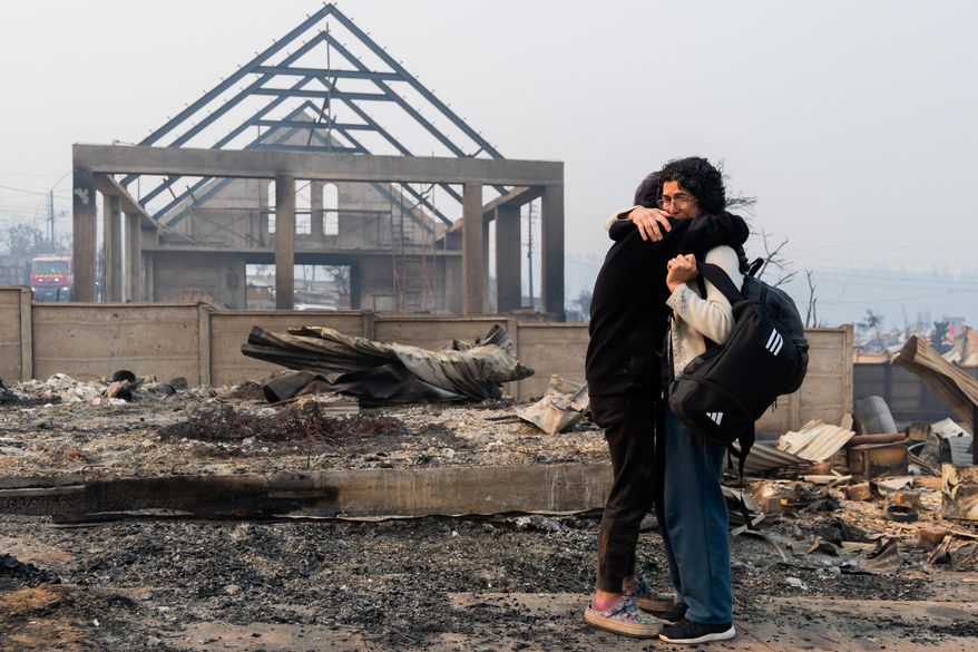 Mirtza Aguilera, right, and her daughter embrace in front of their home burned by wildfires in Tome, Chile, Monday, Jan. 19, 2026. (AP Photo/Javier Torres)