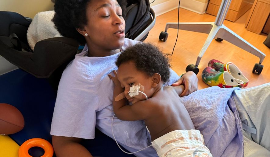 In this photo provided by the family, Ashaan Carter lies on his mother, Angel Carter, at a children's hospital in Portland, Ore., in November 2025, during his treatment for infant botulism after drinking ByHeart baby formula donated to vulnerable families, before a national recall of all of the products. (David Orphey via AP)