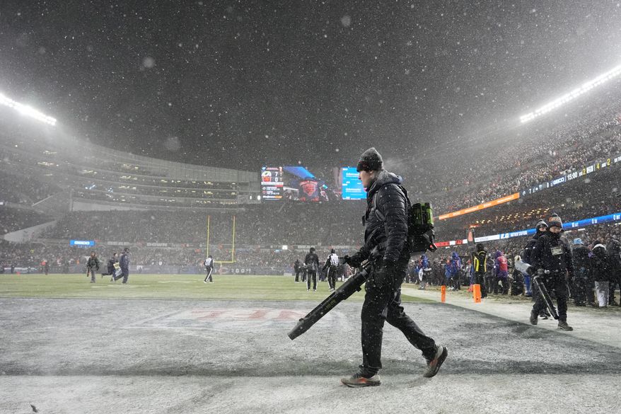 Grounds crew members glow snow off the field at Soldier Field during the first half of an NFL football divisional playoff game between the Chicago Bears and the Los Angeles Rams Sunday, Jan. 18, 2026, in Chicago. (AP Photo/Nam Y. Huh)