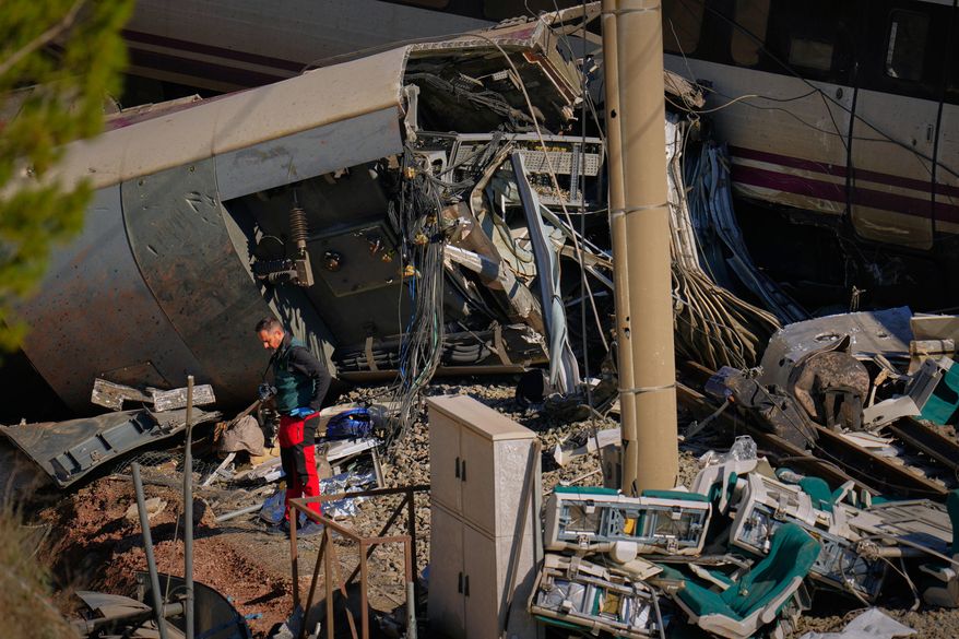 Guardia Civil officers collect evidence next to the wreckage of train cars involved in a collision in Adamuz, southern Spain, Tuesday, Jan. 20, 2026. (AP Photo/Manu Fernandez)