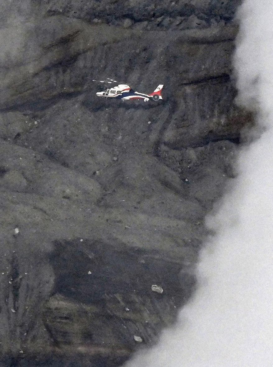 A prefectural disaster prevention helicopter searches near the Nakadake crater of Mount Aso in Kumamoto prefecture, southwestern Japan, Tuesday, Jan. 20, 2026, where a sightseeing helicopter went missing earlier in the day. (Kyodo News via AP)