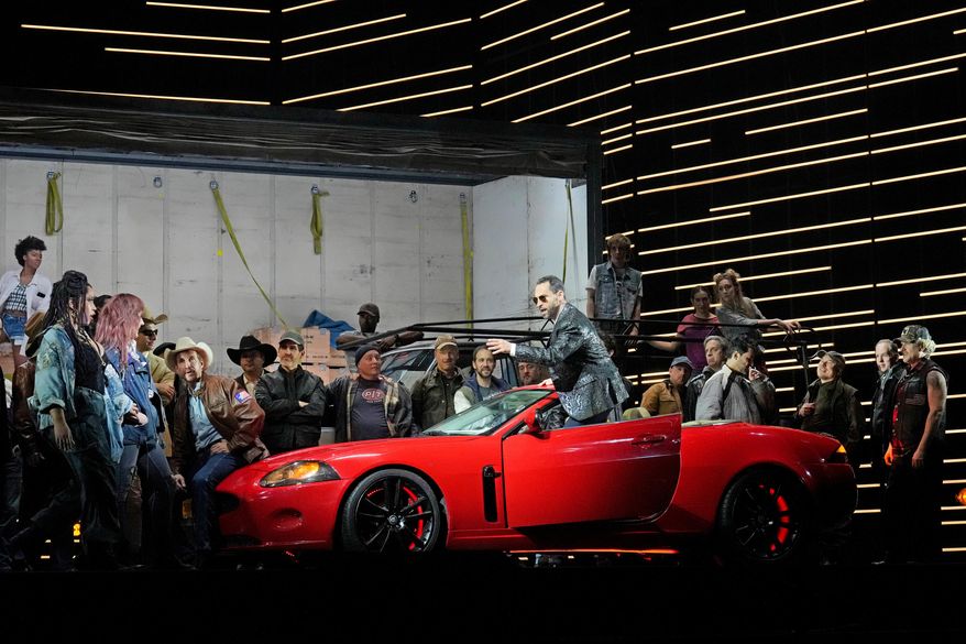 This image released by the Metropolitan Opera shows bass-baritone Kyle Ketelsen, in the red car, during a rehearsal of Bizet’s “Carmen” at the Metropolitan Opera in New York on Dec. 28, 2023. (Ken Howard/Met Opera via AP)