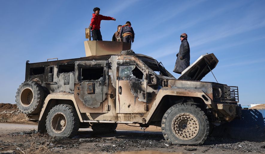 Local youth play atop of a damaged armored vehicle belonging to the Syrian Democratic Forces (SDF) at the site of clashes with Syrian government forces in the village of al-Hol in northeastern Syria's Hasakeh province, Syria, Wednesday, Jan. 21, 2026. (AP Photo/Ghaith Alsayed)