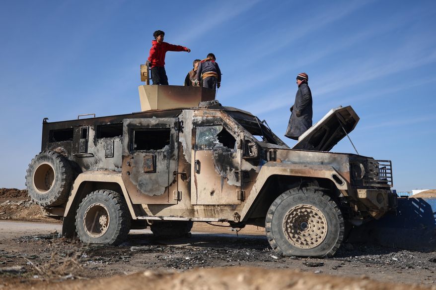 Local youth play atop of a damaged armored vehicle belonging to the Syrian Democratic Forces (SDF) at the site of clashes with Syrian government forces in the village of al-Hol in northeastern Syria's Hasakeh province, Syria, Wednesday, Jan. 21, 2026. (AP Photo/Ghaith Alsayed)
