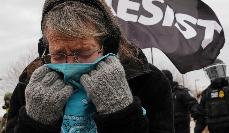 A woman covers her face from tear gas as federal immigration officers confront protesters outside Bishop Henry Whipple Federal Building, Jan. 15, 2026, in Minneapolis. (AP Photo/Adam Gray, File)