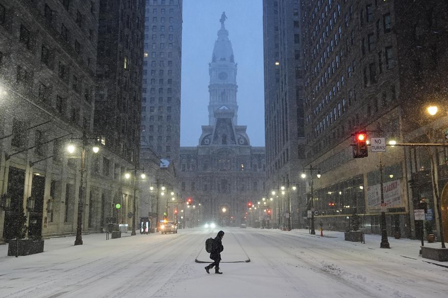 A person walks across a street during a winter storm in Philadelphia, Sunday, Jan. 25, 2026. (AP Photo/Matt Rourke)
