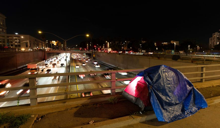 FILE - A tarp covers a portion of a homeless person's tent on a bridge overlooking the 101 Freeway in Los Angeles, Feb. 2, 2023. (AP Photo/Jae C. Hong, File)