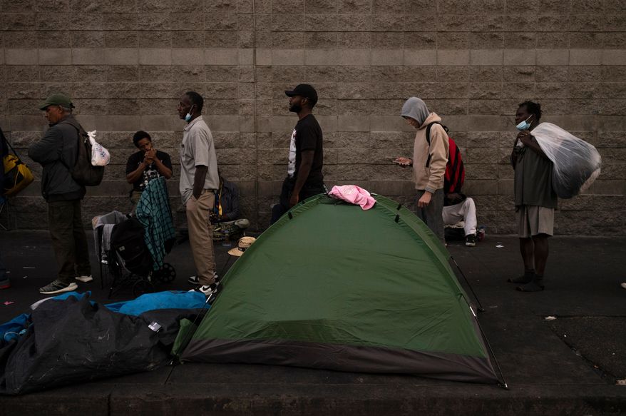 FILE - Homeless people wait in line for dinner outside the Midnight Mission in the Skid Row area of Los Angeles, Oct. 25, 2023. (AP Photo/Jae C. Hong, File)