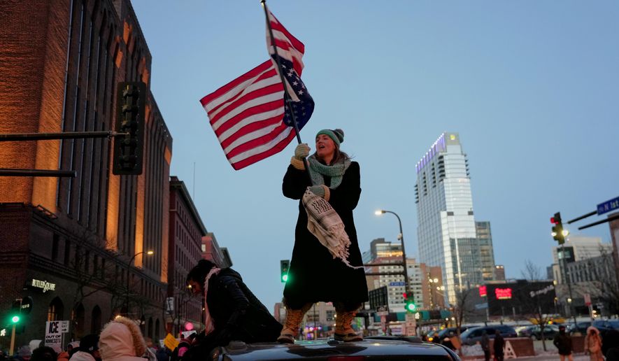 Teresa Hurst waves an upside-down American flag on top of a car during a rally against federal immigration enforcement on Friday, Jan. 23, 2026, in Minneapolis. (AP Photo/Angelina Katsanis)
