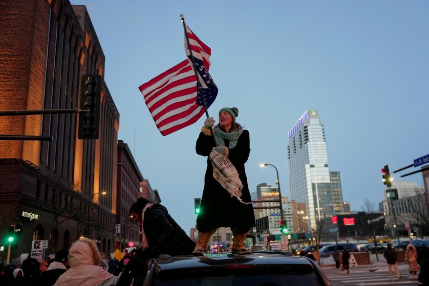 Teresa Hurst waves an upside-down American flag on top of a car during a rally against federal immigration enforcement on Friday, Jan. 23, 2026, in Minneapolis. (AP Photo/Angelina Katsanis)