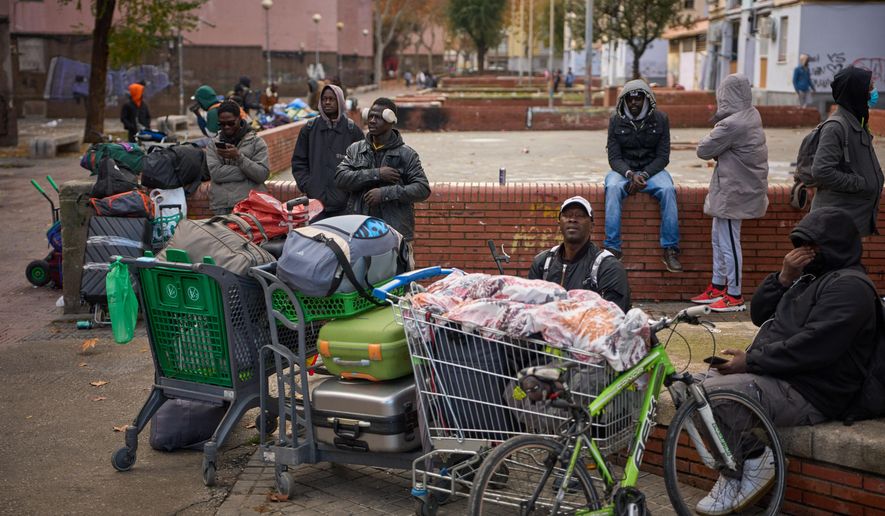 Migrants sit together with their belongings after being evicted by police from an abandoned school where they had been living in Badalona, near Barcelona, Spain, Wednesday, Dec. 17, 2025. (AP Photo/Emilio Morenatti, File)