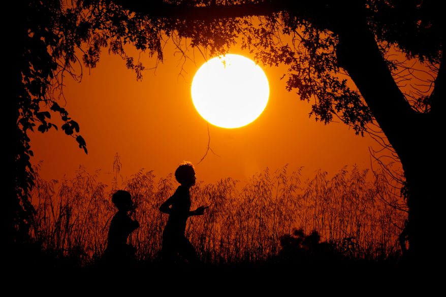 People are silhouetted against the sky at sunset as they run at Shawnee Mission Park in Shawnee, Kan., on Sept. 26, 2024. (AP Photo/Charlie Riedel) **FILE**