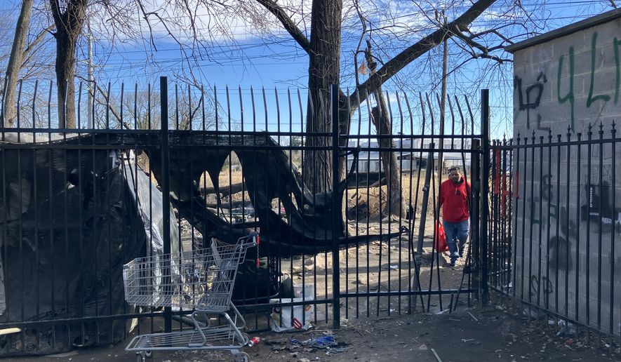 Unidentified people shuffle into the Marylander Condominiums through a gap in the security fence on Monday, Jan. 12. Property managers say unknown vagrants created the opening when workers installed the fence last year. (Sean Salai/The Washington Times)