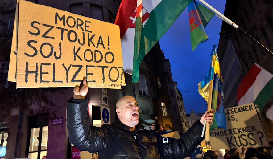 A woman holds a sign that reads "Hey Sztojka, what's the deal?" at a protest called against a Hungarian government minister for comments he made about the Roma minority, in Budapest, Hungary, Saturday, Jan. 31, 2026. (AP Photo/Bela Szandelszky)