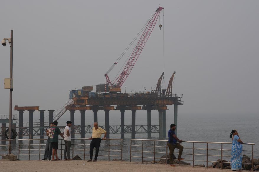 People stand near the site of the under-construction coastal road in Mumbai, India, Sunday, Feb. 1, 2026. (AP Photo/Rafiq Maqbool)
