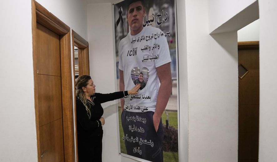 Raweah Safiya palms a poster bearing the image of her son, Nabil, who was shot dead in last November in a case of mistaken identity, a victim of gang-related violence, in Kafr Yasif, northern Israel, Sunday, Jan. 18, 2026. (AP Photo/Mahmoud Illean)