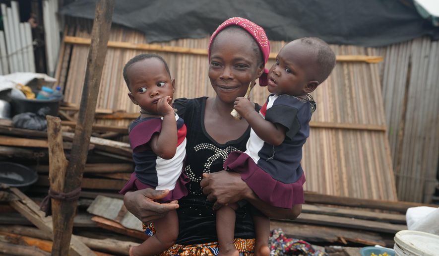 Josianua Agbokpasu poses with her twins at their demolished stilts house in Makoko Lagos, Nigeria, Friday, Jan.30, 2026. (AP Photo/Sunday Alamba)