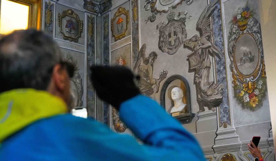 People take pictures at a restored fresco to the memory of late Italy's King Umberto II depicting Angels inside the Basilica of St. Lawrence in Lucina in Rome, Sunday, Feb. 1, 2026. (AP Photo/Gregorio Borgia)