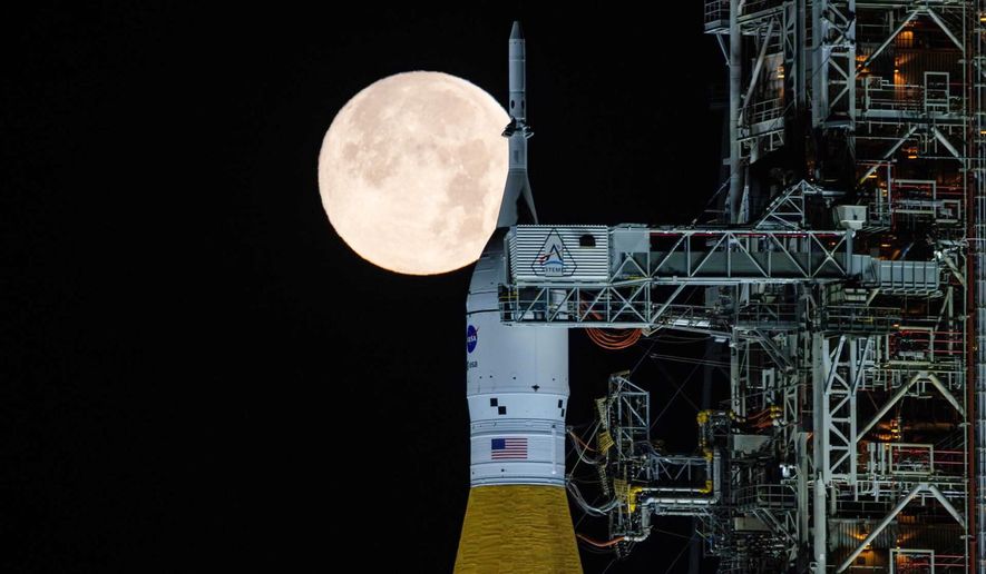 A full moon is seen shining over NASA’s SLS (Space Launch System) and Orion spacecraft, atop the mobile launcher in the early hours of Sunday, Feb. 1, 2026, at NASA’s Kennedy Space Center in Florida. (Sam Lott/NASA via AP)