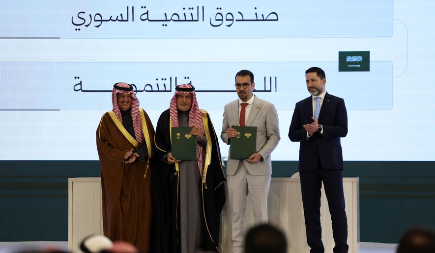 Officials pose after signing a framework agreement for developmental cooperation and the launch of 45 development initiatives between the Syrian Development Fund and Saudi Arabia's Development Committee at the People's Palace in Damascus, Syria, Saturday, Feb. 7, 2026. (AP Photo/Ghaith Alsayed)