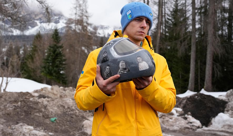 Ukrainian skeleton athlete Vladyslav Heraskevych holds his crash helmet as he stands outside the sliding center at the 2026 Winter Olympics, in Cortina d'Ampezzo, Italy, Thursday, Feb. 12, 2026. (AP Photo/Alessandra Tarantino)