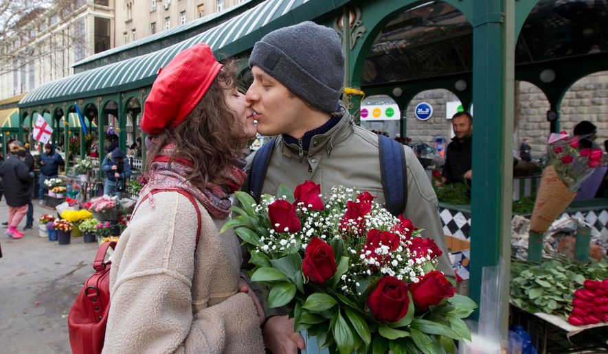 A couple share a tender moment near a flower market celebrating International Women's Day in Tbilisi, Georgia, March 8, 2022. (AP Photo/Shakh Aivazov, File)