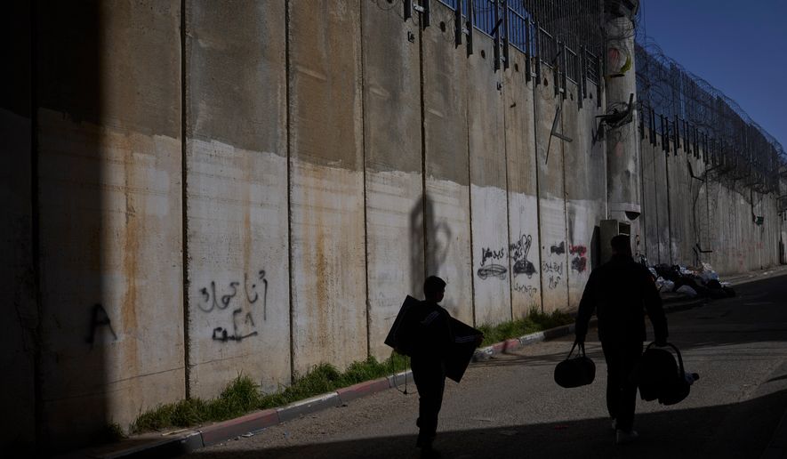 Palestinians walk along the separation barrier between the West Bank and east Jerusalem neighborhood of Beit Hanina, Sunday Feb. 15, 2026. (AP Photo/Ohad Zwigenberg)