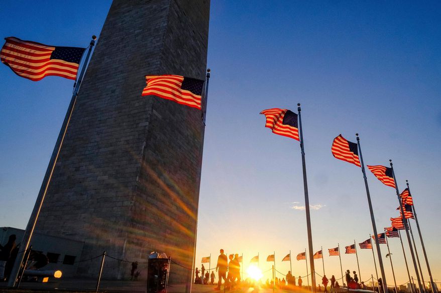 FILE - Tourists walk around the base of the Washington Monument on Presidents Day weekend as the sunsets, Feb. 19, 2017, in Washington. (AP Photo/J. David Ake, file)