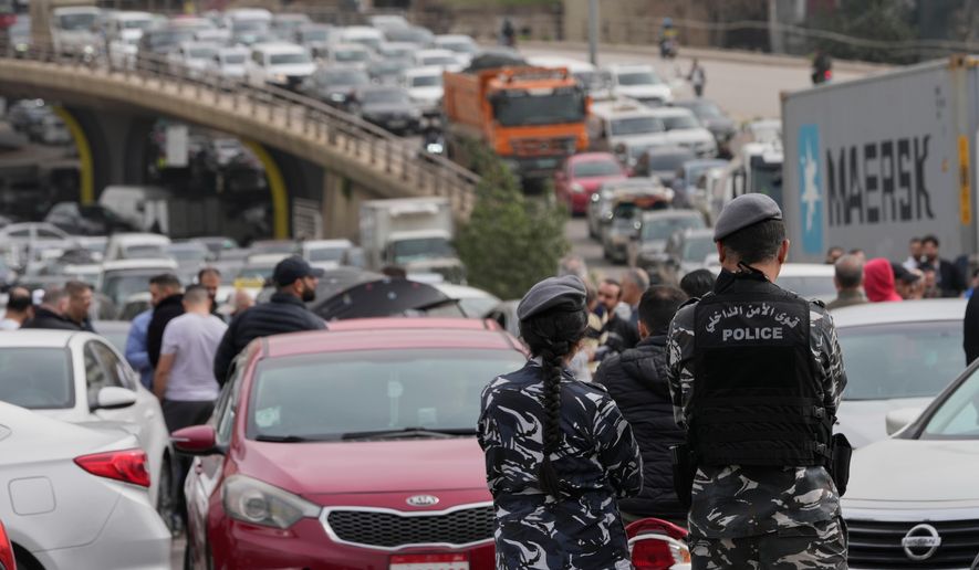 Lebanese police stand in front of taxi drivers who block a main highway with their cars during a protest against the increased taxes and gasoline prices issued by the Lebanese Cabinet on Monday, in Beirut, Lebanon, Tuesday, Feb. 17, 2026. (AP Photo/Hussein Malla)