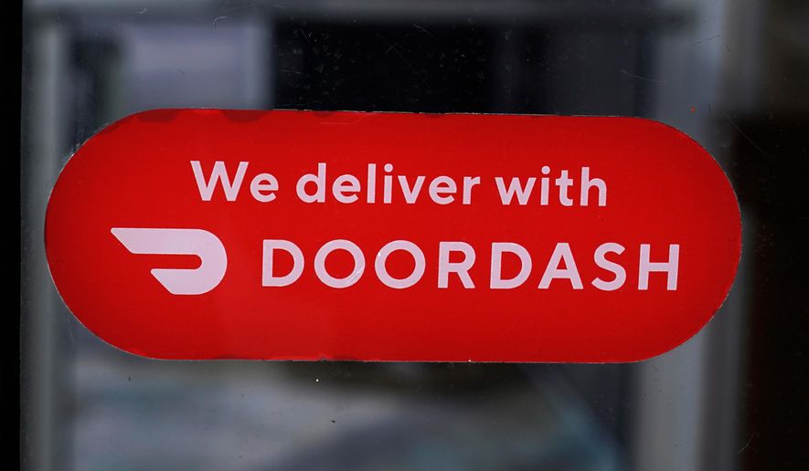 A DoorDash sign is posted on the door of a Dunkin' Donuts franchise, Feb. 27, 2023, in Methuen, Mass. (AP Photo/Charles Krupa, File)