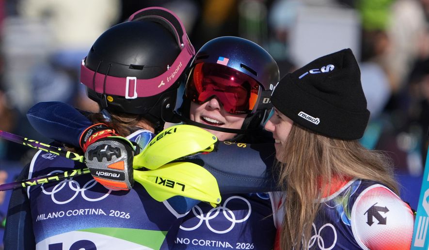 United States' Mikaela Shiffrin, center, winner of an alpine ski, women's slalom race, is congratulated by second-placed Switzerland's Camille Rast, right, and third-placed Sweden's Anna Swenn Larsson, at the 2026 Winter Olympics, in Cortina d'Ampezzo, Italy, Wednesday, Feb. 18, 2026. (AP Photo/Jacquelyn Martin)