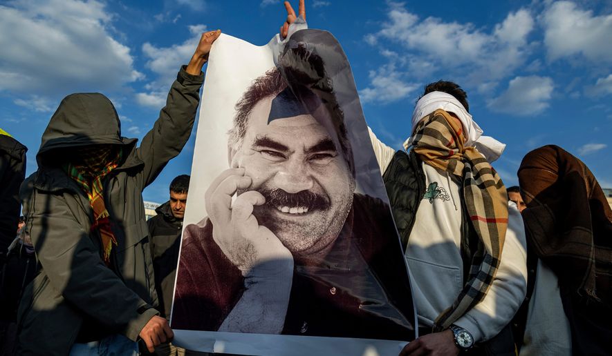 FILE - Youngsters hold a photograph of Abdullah Ocalan, the jailed leader of the militant Kurdish group, or PKK, in Diyarbakir, Turkey, Feb. 27, 2025. (AP Photo/Metin Yoksu, File)