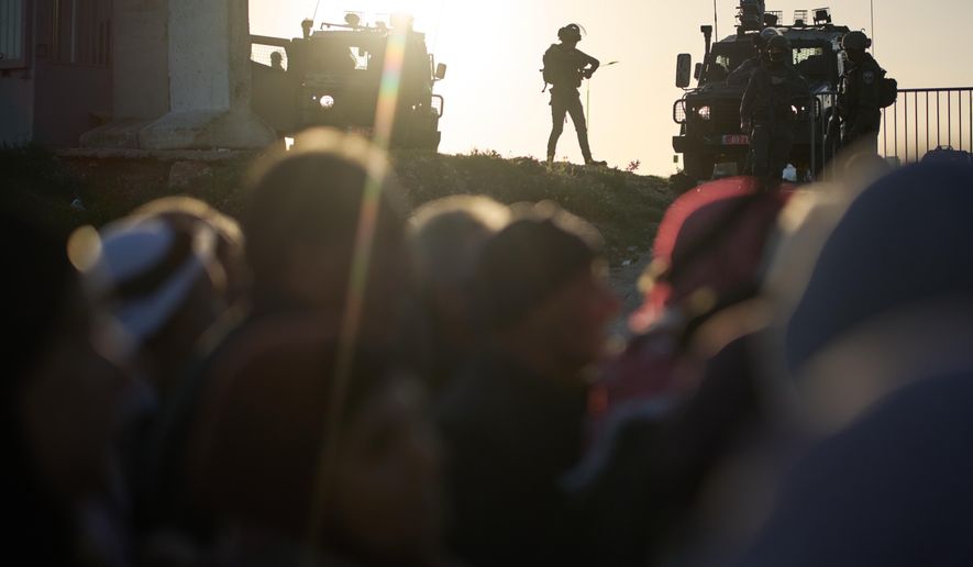 Israeli soldiers stand guard as Palestinian worshippers line up to pass through the Israeli military Qalandia checkpoint between the West Bank city of Ramallah and Jerusalem on their way to attend Friday prayers at Al-Aqsa Mosque during the Muslim holy month of Ramadan, Friday, Feb. 20, 2026. (AP Photo/Leo Correa)