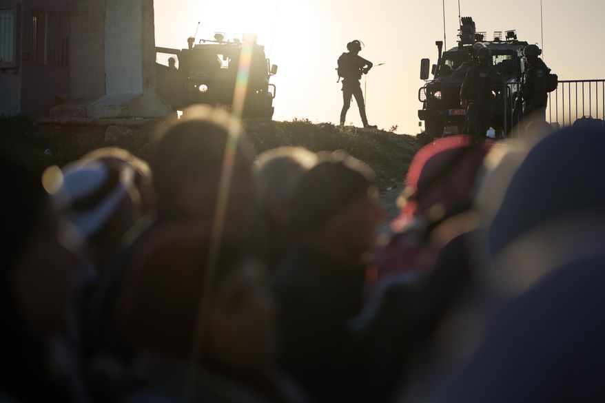 Israeli soldiers stand guard as Palestinian worshippers line up to pass through the Israeli military Qalandia checkpoint between the West Bank city of Ramallah and Jerusalem on their way to attend Friday prayers at Al-Aqsa Mosque during the Muslim holy month of Ramadan, Friday, Feb. 20, 2026. (AP Photo/Leo Correa)