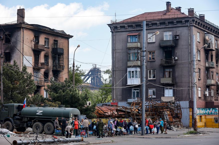 Civilians gather to receive drinking water distributed by the Russian Emergency Situations Ministry in Mariupol on May 27, 2022, after the seaside city in eastern Ukraine fell to Moscow's troops. (AP Photo, File)