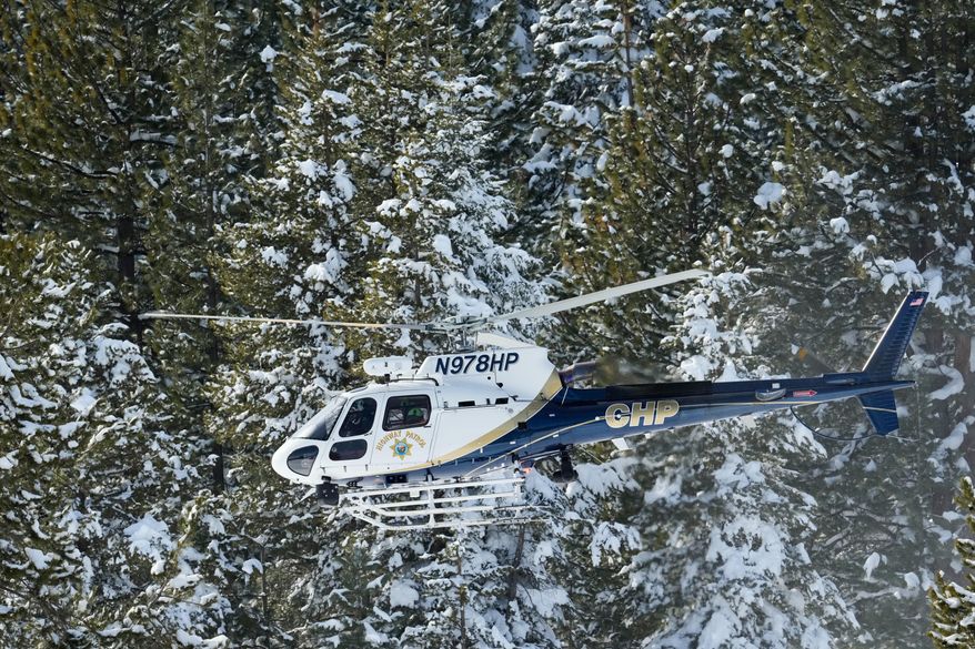 A California Highway Patrol search and rescue crew flies over a forest as recovery efforts for a group of missing skiers continue Friday, Feb. 20, 2026, in Truckee, Calif. (AP Photo/Godofredo A. Vásquez)