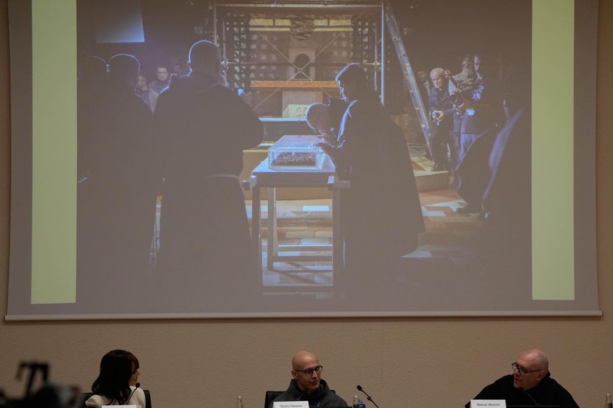 From left, TV Lorena Bianchetti, Friar Giulio Cesareo director of the communications office of the Basilica of St. Francis, and Friar Marco Moroni, Custodian of the Sacred Convent, show journalists the the moment when the saint's bones were extracted from the reliquary in Assisi, Italy, Saturday, Feb. 21, 2026, on the eve of the public display of St. Francis' remains to mark the 800th anniversary of his death in 1226.(AP Photo/Gregorio Borgia)